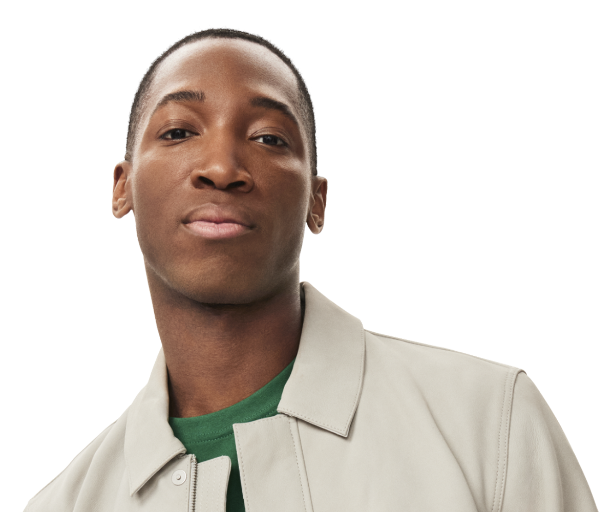 Image of a man in a light-colored jacket and green shirt, tilting his head slightly, with a calm and composed expression.