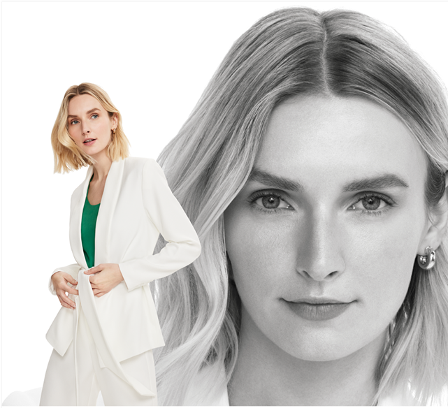 A woman in a white suit with a green top underneath, striking a confident pose.